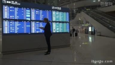 年轻女子在机场使用电子平板电脑，并查看电子<strong>航班</strong>时刻表